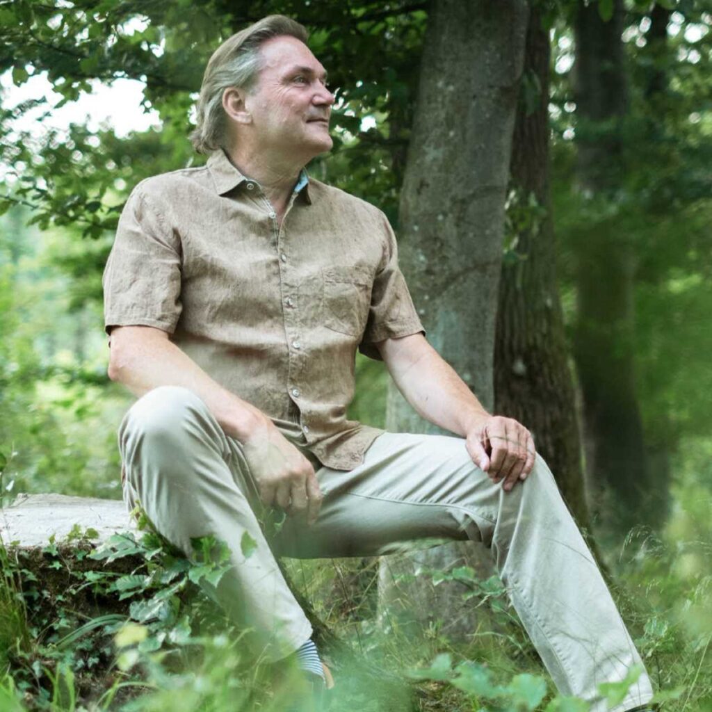 Alfred Steinke sitzend im grünen Laubwald. Ganzheitliche Beratung in Linz - Harmonie in Körper | Geist | Seele